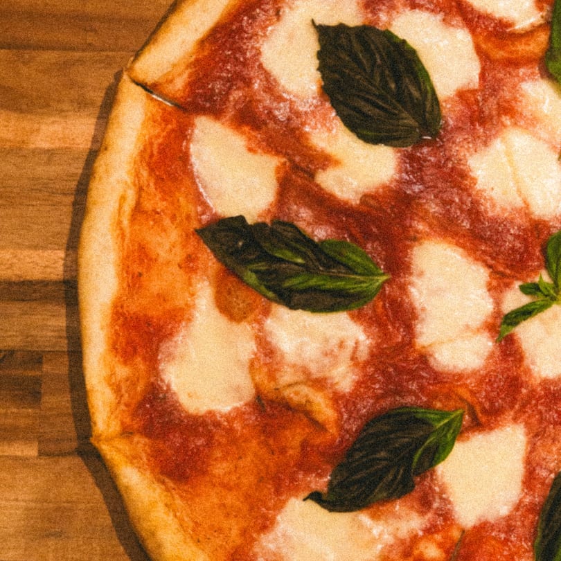 Close-up of a Big City Slices Margherita pizza with fresh basil leaves and melted mozzarella.